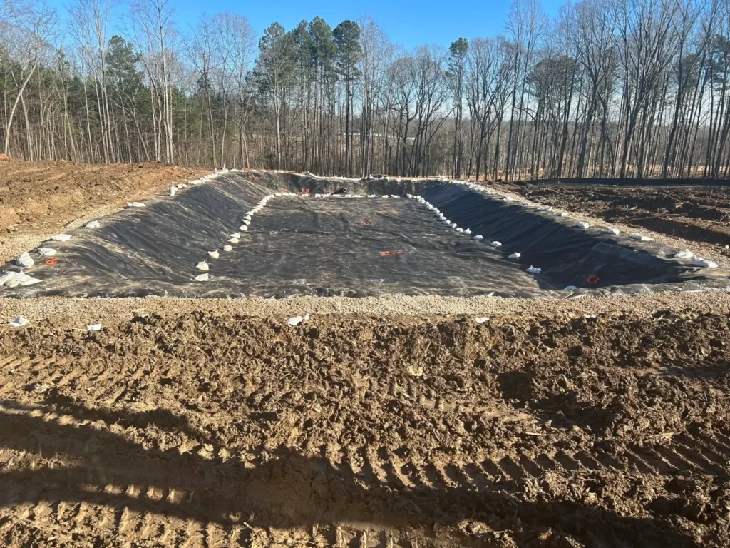 Under-construction rectangular water reservoir in forest clearing.
