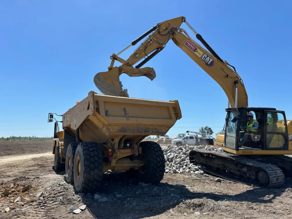 Excavator loading rocks into dump truck at construction site