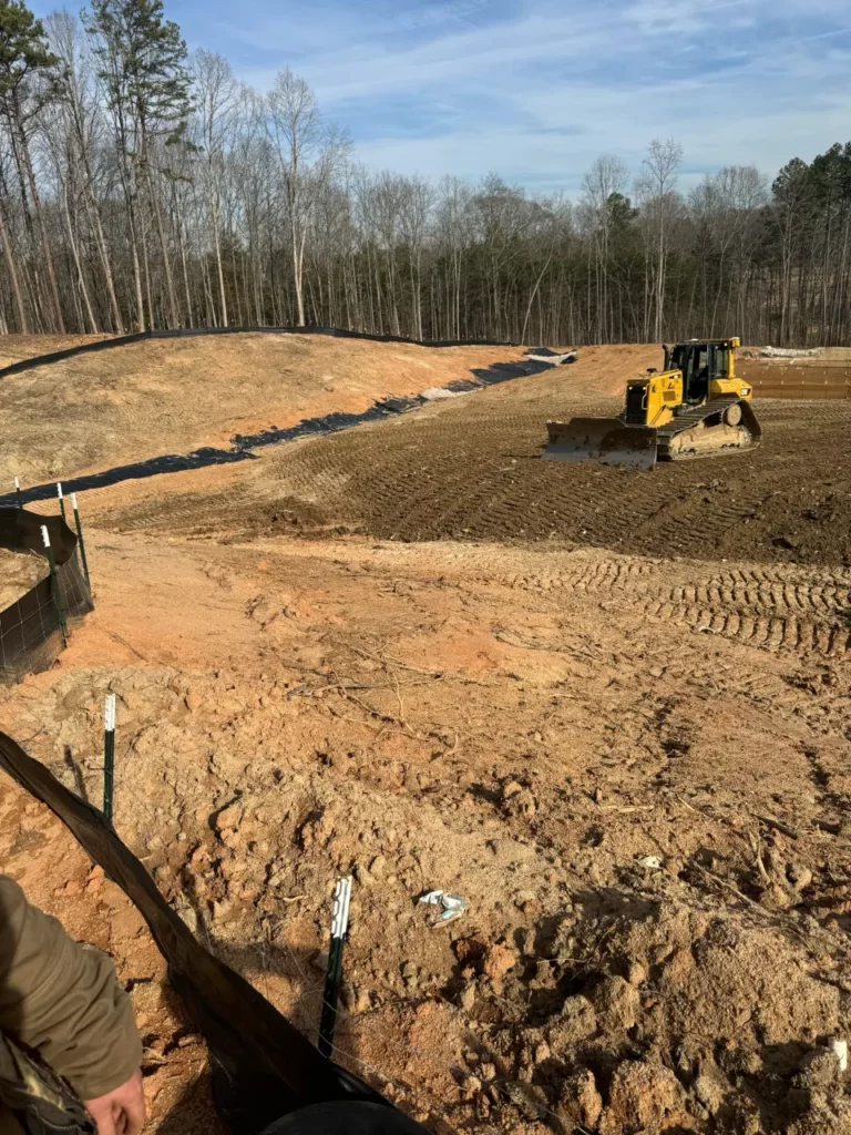 Excavator on construction site with forest backdrop
