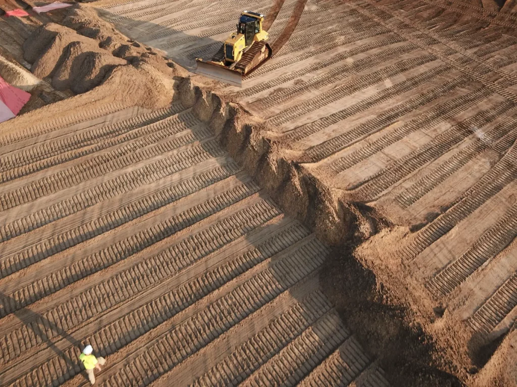 Bulldozer grading earth on construction site at sunset