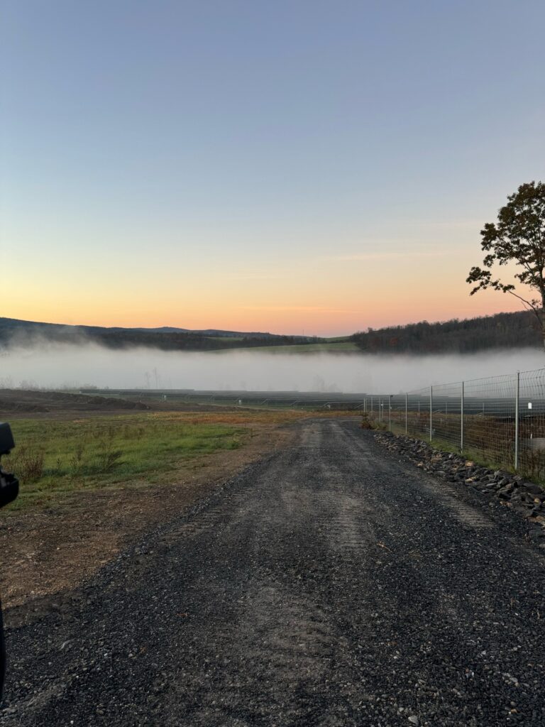 Misty sunrise over a rural gravel road and hills